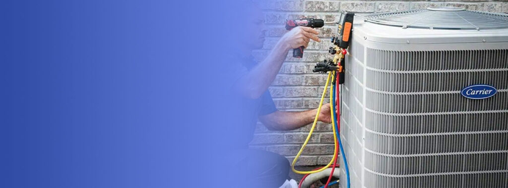 Technician checking refrigerant pressures with gauges on an outdoor Carrier air conditioner condenser during a spring tune-up.